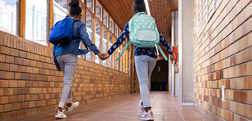 two students walking down hallway holding hands